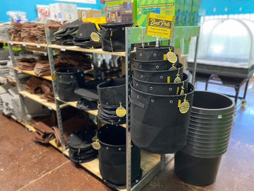 BudTrainer BudPots fabric grow bags stacked and displayed on retail store shelves for cannabis cultivation.