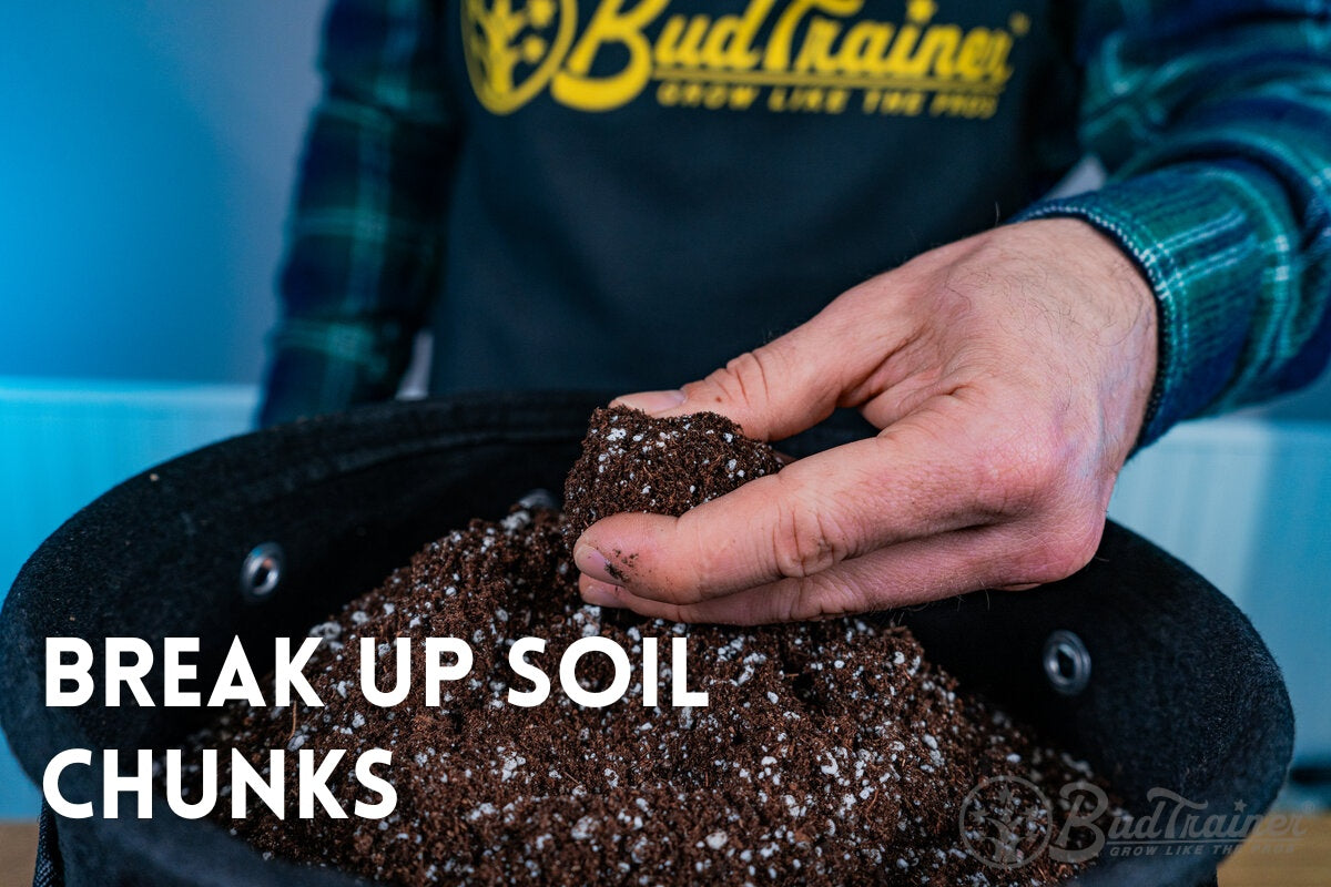 Hand breaking up a chunk of soil with perlite inside the BudPots, wearing an apron that says BudTrainer in the background.