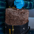 Gardener using BudTrainer BudPots fabric pot filled with soil for cannabis transplanting.