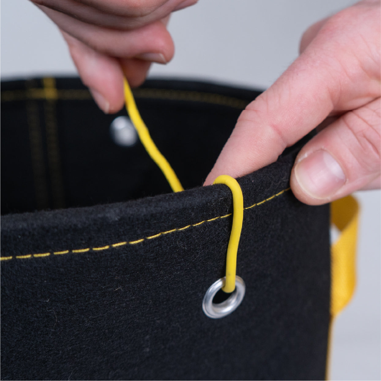 Close-up of BudTrainer BudPots fabric pot with training wire threaded through metal grommet for easy plant training.