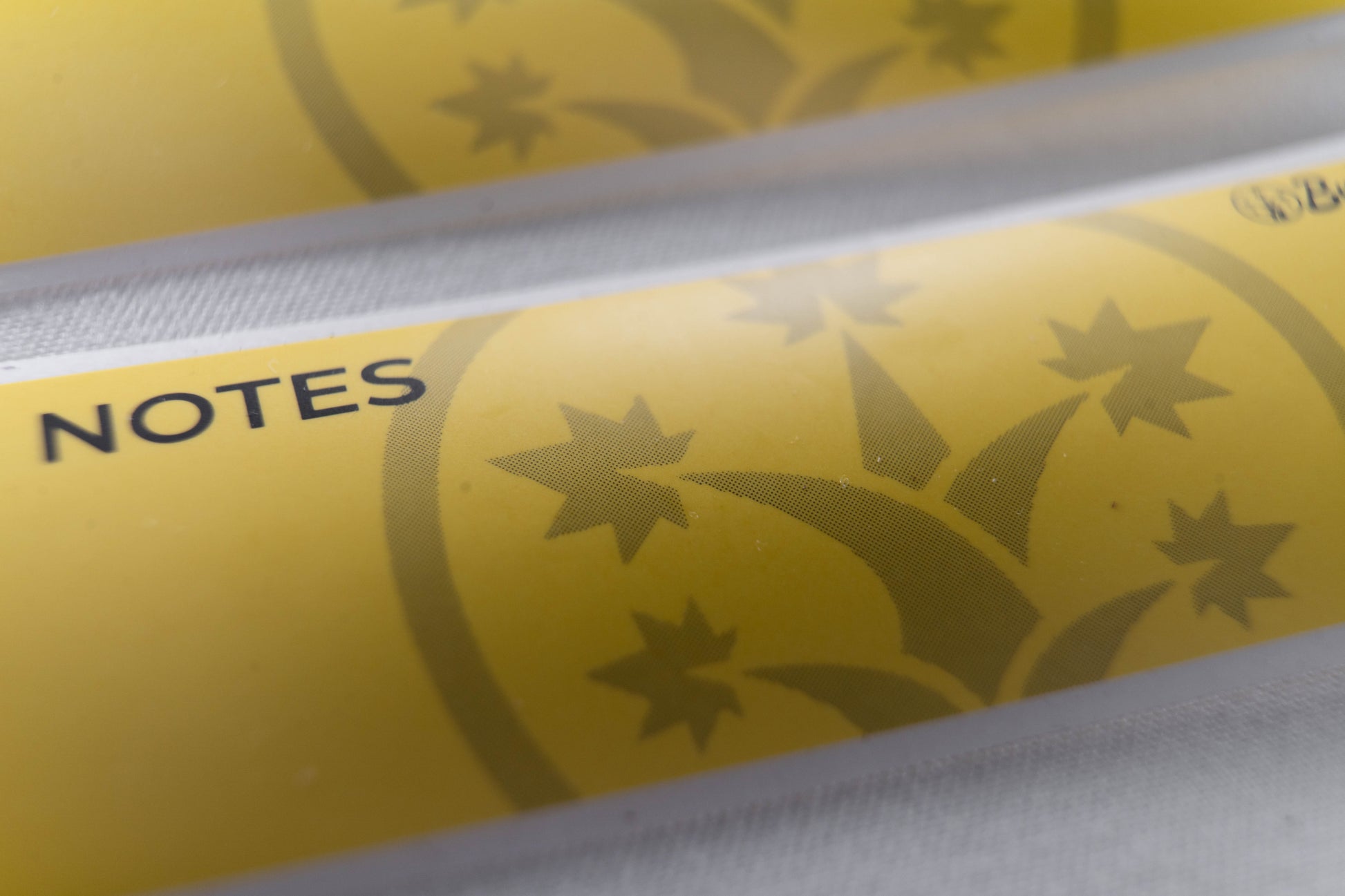 Macro shot of BudTrainer yellow sticky notes with cannabis grow logo and notes section.